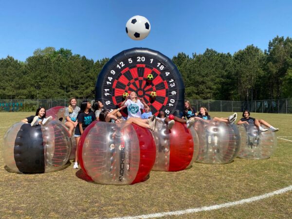 Kids playing knockerball bubble soccer in a field